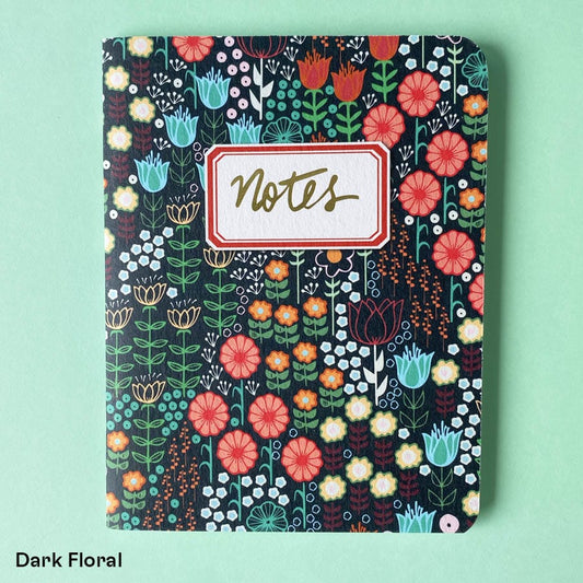 Pocket sized notebook with a dark floral patterned covered and vintage style notes label in gold foil